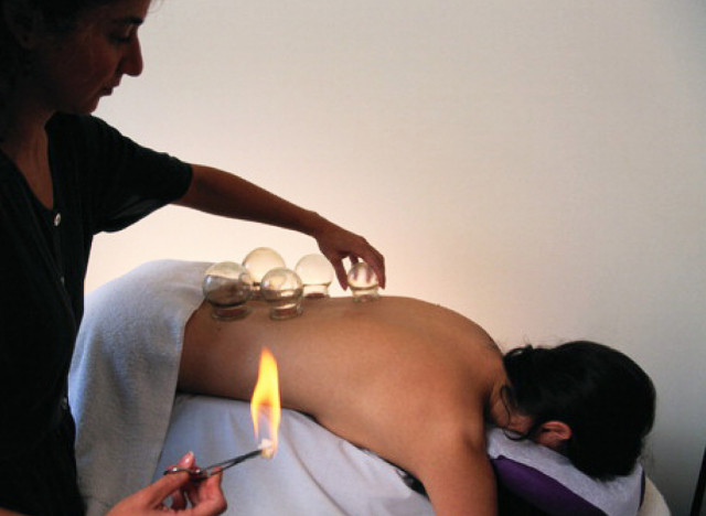 Rücken mit Schröpfgläser und Flamme